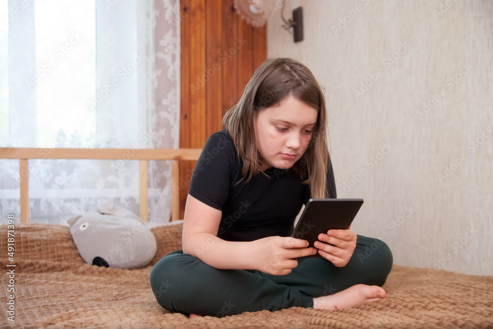 Schoolgirl girl on bed at home with tablet. Schoolgirl girl on bed at home with tablet.