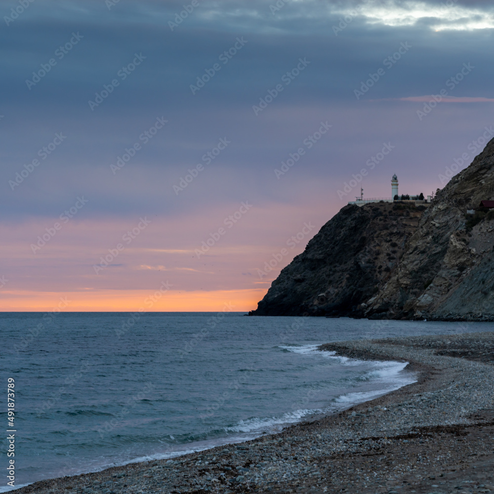 view of La Chucha Beach and the lighthouse of Cabo Sacratif in Andalusia at asunset
