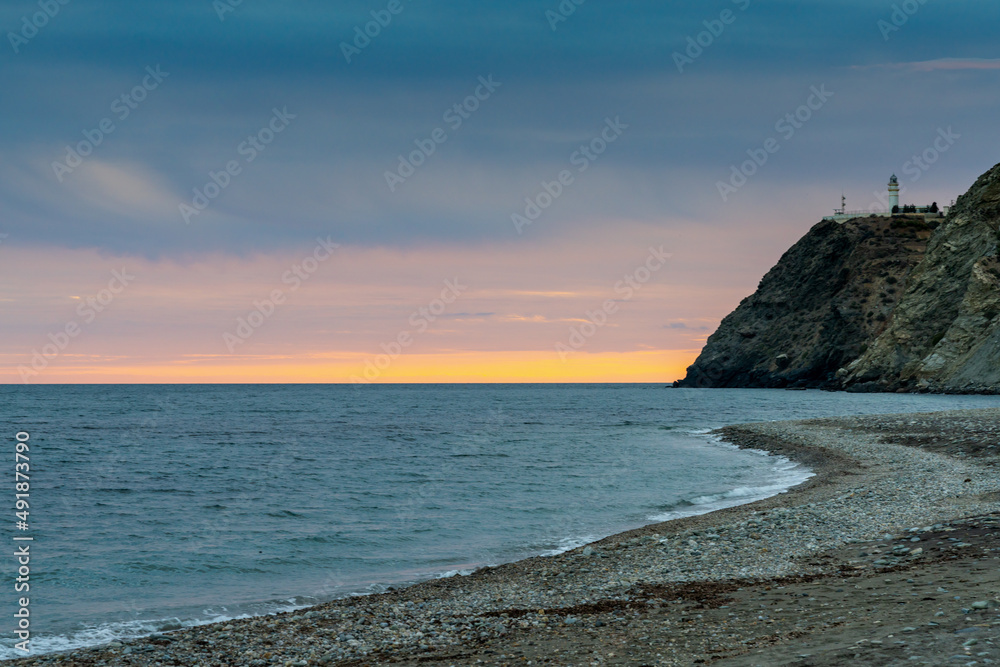 view of La Chucha Beach and the lighthouse of Cabo Sacratif in Andalusia at asunset
