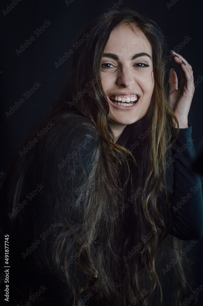 Portrait of a beautiful young woman with very long hair who laughs cheerfully and brings her hand close to her head Portrait of a beautiful young woman with very long hair who laughs cheerfully and brings her hand close to her head