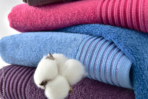 A stack of colored bath towels with a cotton flower. Face towels