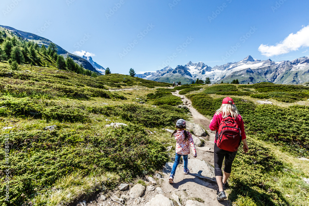 Happy family with little child doing trekking on switzerland mountain in summer time. Young people having fun in landscape nature. Concept of travel, friendly family