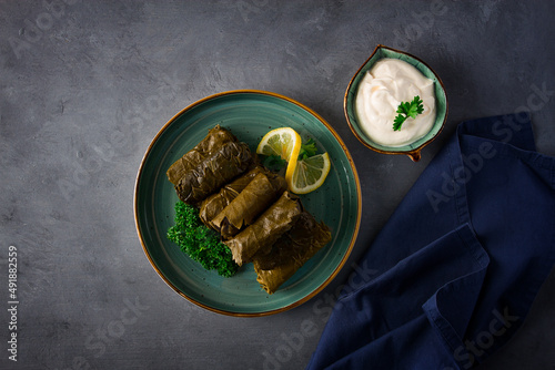 Dolma, cabbage rolls, grape leaves with filling, white sauce, lemon and herbs, rustic, selective focus, no people, photo