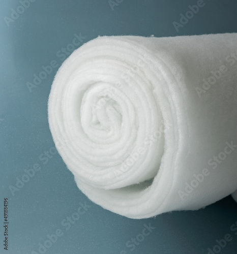 A roll of padding polyester on a blue background. Large skein of synthetic winterizer photo