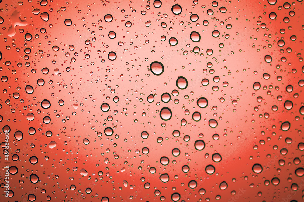 droplets of rain on a glass window, red background