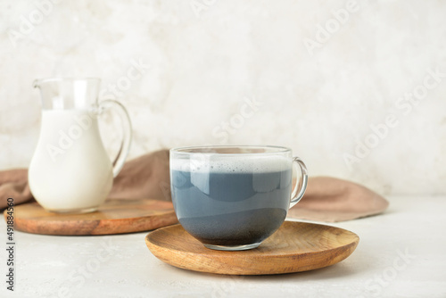 Wooden plate with glass cup of delicious Charcoal Latte on light background