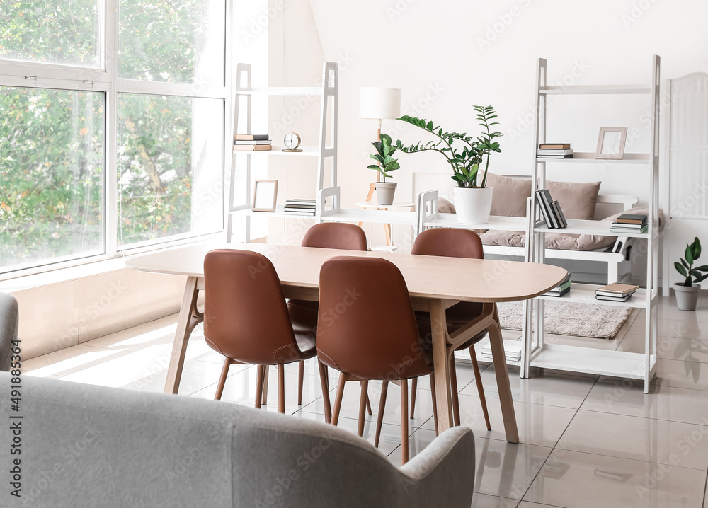 Interior of light room with book shelves, dining table and couch