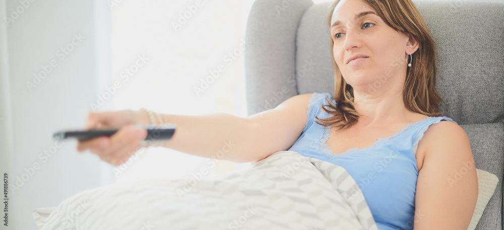 Young adult woman wearing casual clothes holds the tv remote control to change the show. Real people concept. Young adult woman wearing casual clothes holds the tv remote control to change the show. Real people concept.
