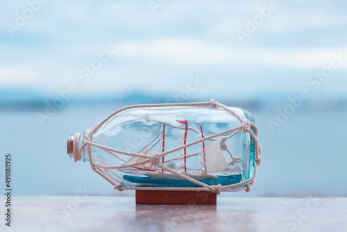 nautical concept image with sail boat in the bottle on the beach background