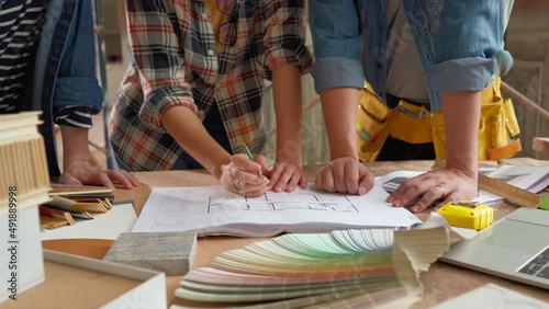 Groups of people having discussion with blueprint on the table at constructions site atmosphere.