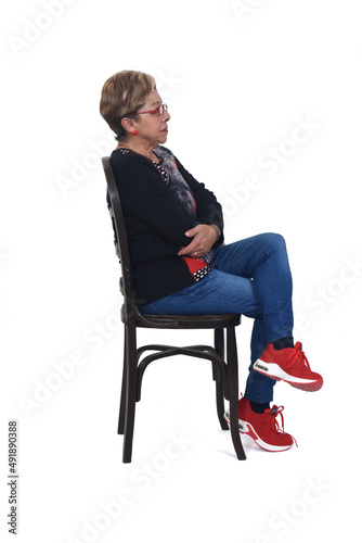 side view of a full portrait of serious woman  sitting on chair on white background © curto