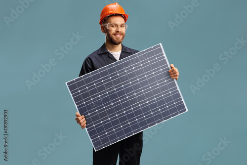 Young male worker in a unifrom holding a solar cell photovoltaic module photo