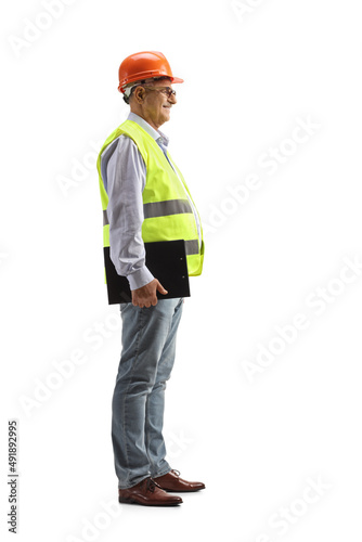 Full length profile shot of a mature male engineer with a safety vest and hardhat holding a clipboard © Ljupco Smokovski