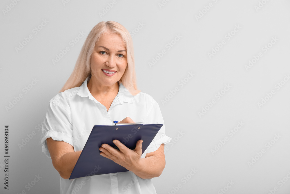 Mature secretary with clipboard on light background Mature secretary with clipboard on light background