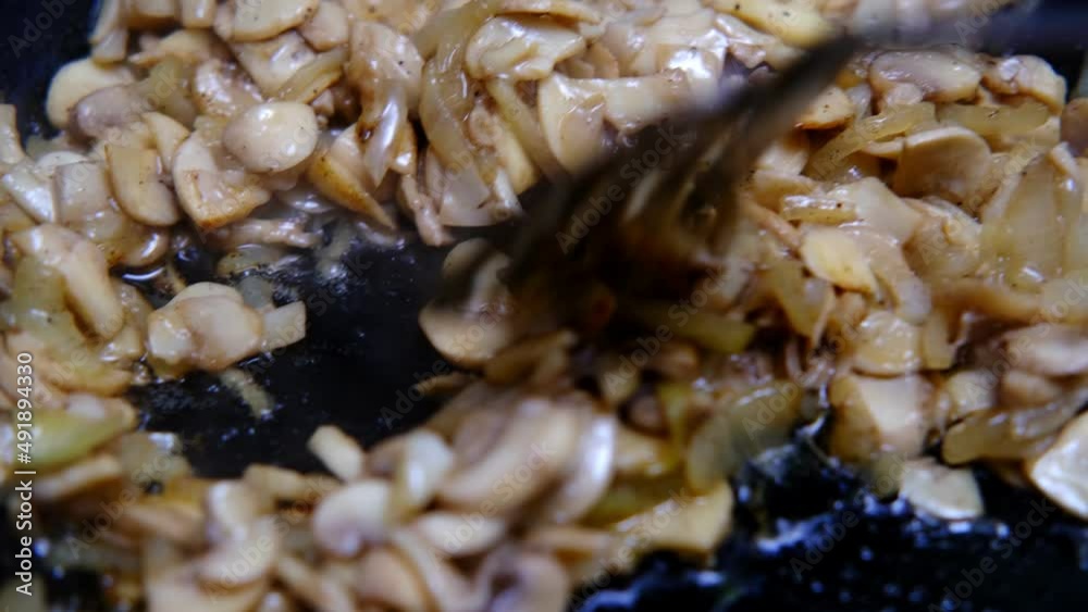 Fry mushrooms with onions in a pan. Close-up. The spatula stirs. Fry mushrooms with onions in a pan. Close-up. The spatula stirs.