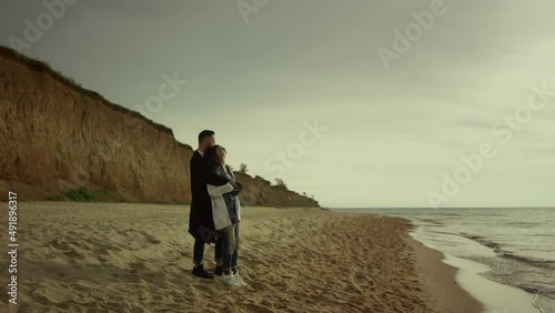 Couple cuddling beach sea on holiday. Happy mixed race lovers hug at ocean shore photo