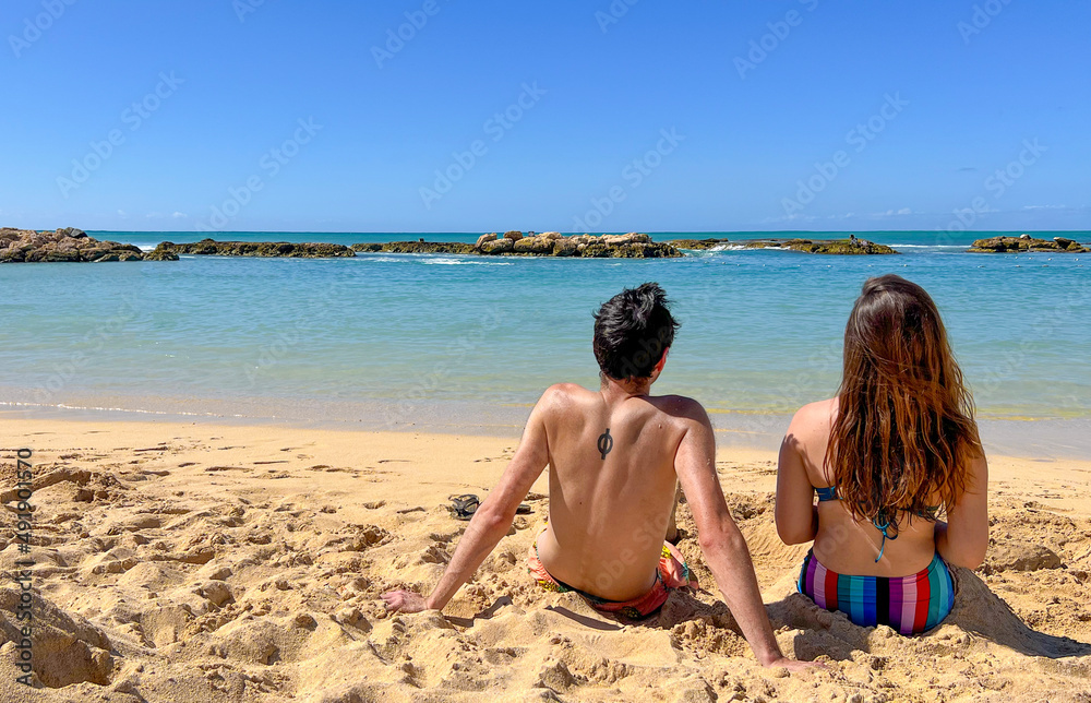 Couple sunbathing on the beach in Hawaii. Both have their backs turned. They're Watching the Sea. Paradise island Hawaii, Honululu