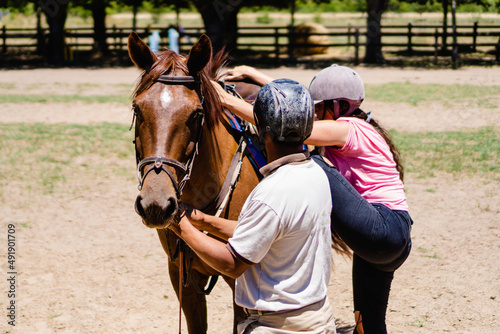 riding instructor, teaching a young woman how to get on the horse © juanpablo