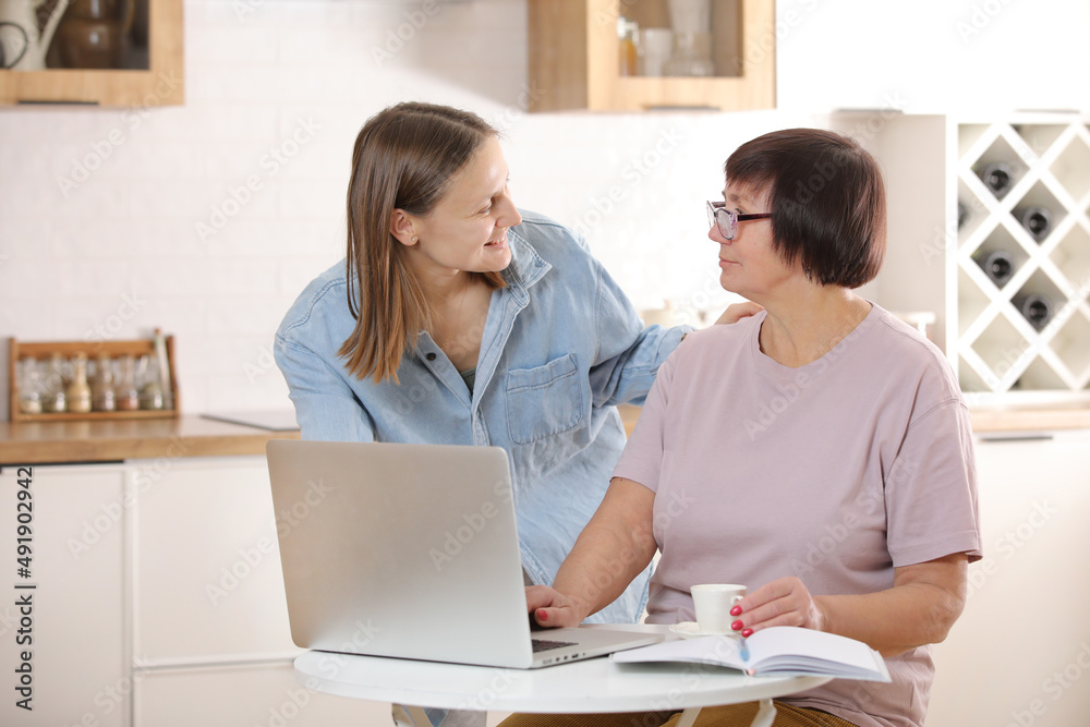 young woman teaching senior mother to use internet on laptop at home. daughter helps her elderly mother figure it out online with her personal account, teaches at modern gadget indoors. young woman teaching senior mother to use internet on laptop at home. daughter helps her elderly mother figure it out online with her personal account, teaches at modern gadget indoors.