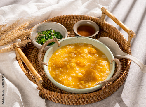 Congee pumpkin corn congee with spring onion in a dish side view on grey background photo