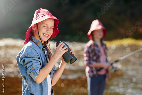 Enjoying a day of adventure along the river. A young girl holding a pair of binoculars in the outdoors.