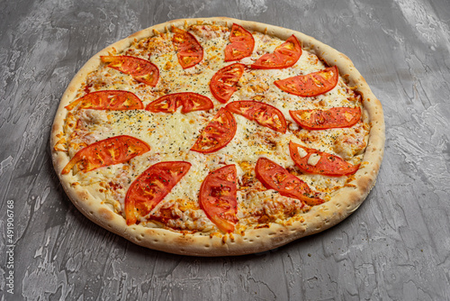 Margherita pizza with utensils and vegetable on slate plate