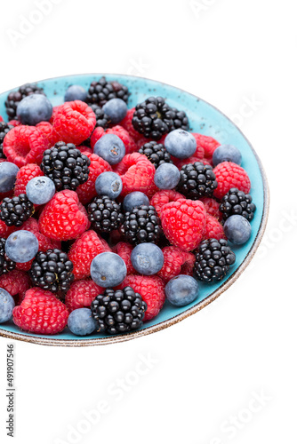 Fresh berry salad on blue dishes. Vintage wooden background.