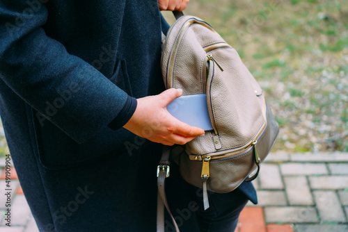 Young woman put smart phone into bag.