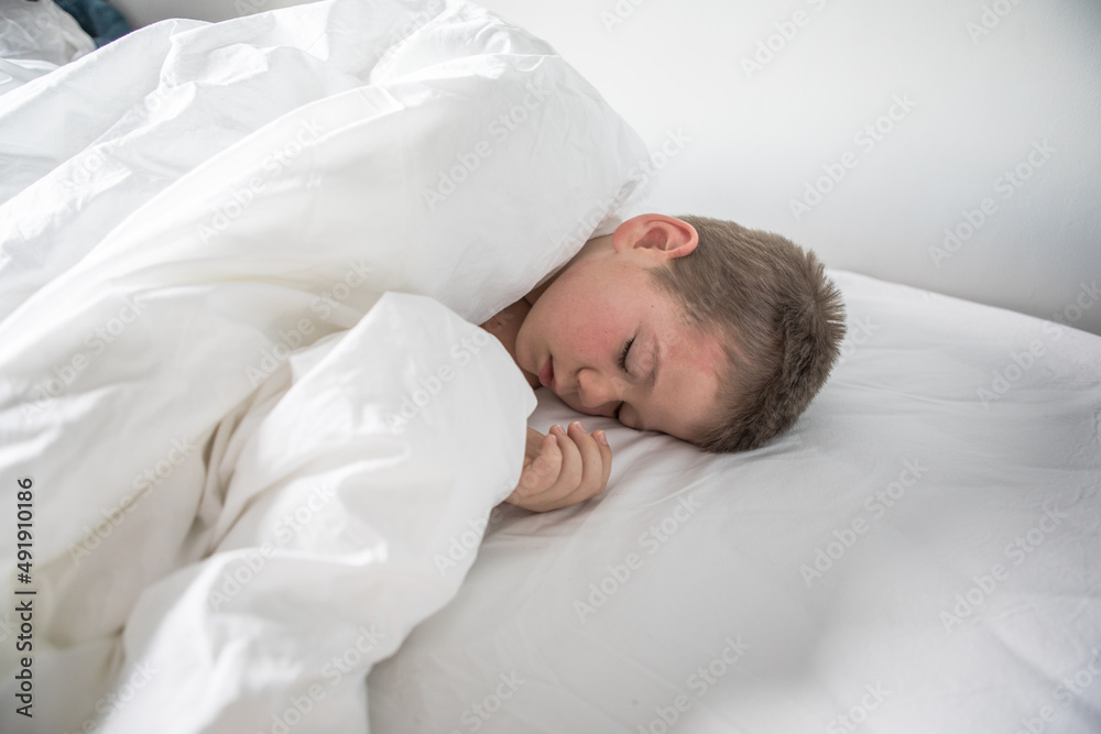 Kid 7 year old lying on bed, Sleepy child waking up the morning in his bed room with morning light Kid 7 year old lying on bed, Sleepy child waking up the morning in his bed room with morning light