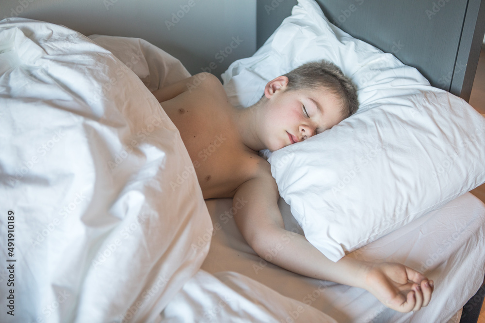 Kid 7 year old lying on bed, Sleepy child waking up the morning in his bed room with morning light Kid 7 year old lying on bed, Sleepy child waking up the morning in his bed room with morning light