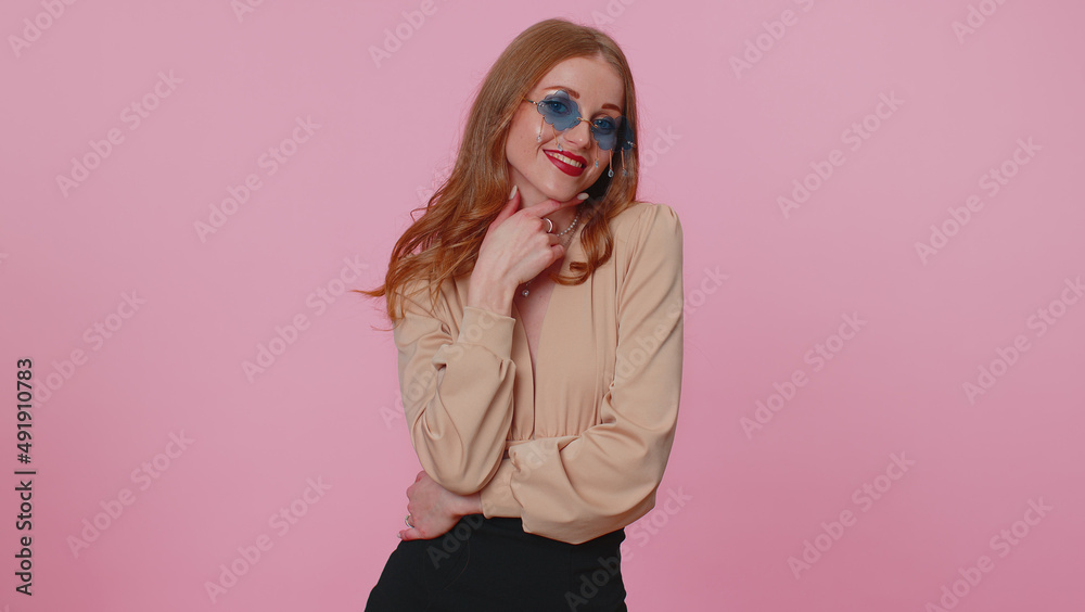 Sincere lovely cheerful cool businesswoman girl in beige blouse wearing red sunglasses, charming smile. People emotions concept. Young lovely adult woman posing isolated on pink studio wall background Sincere lovely cheerful cool businesswoman girl in beige blouse wearing red sunglasses, charming smile. People emotions concept. Young lovely adult woman posing isolated on pink studio wall background