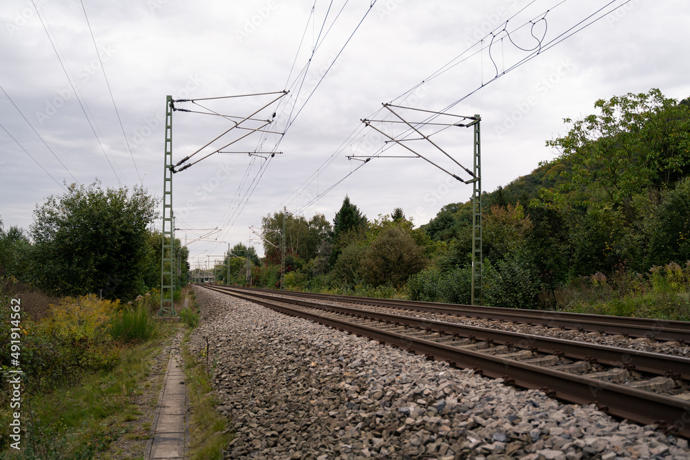 Two railway tracks in a rural environment on an autumn day with cloudy sky