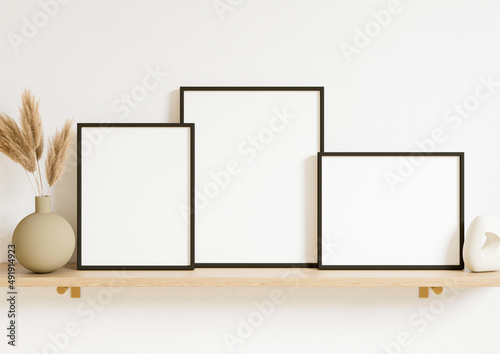 Boho Style Vertical and horizontal 8x10 three Black Frames mockup. Vertical Black frame on a wooden shelf with plant in a vase. 3d rendering.