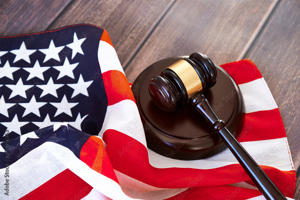 Judge's gavel and american flag on wooden table.
