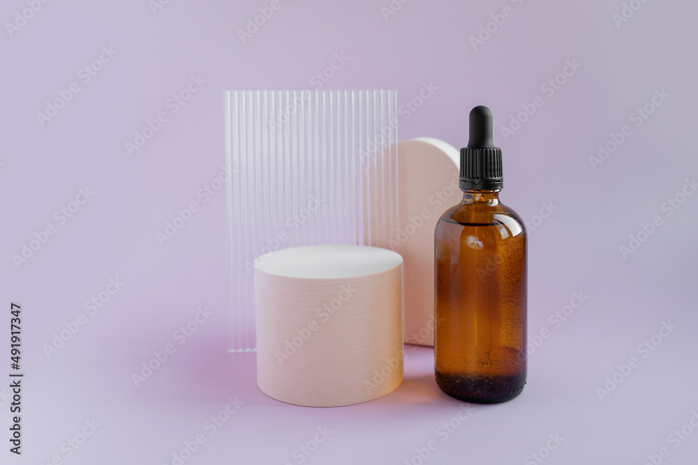 Cosmetic bottle made of dark amber glass without labels on a bright lilac background with geometric shapes. With place for your design. Minimalist brand packaging mockup. Cosmetic bottle made of dark amber glass without labels on a bright lilac background with geometric shapes. With place for your design. Minimalist brand packaging mockup.