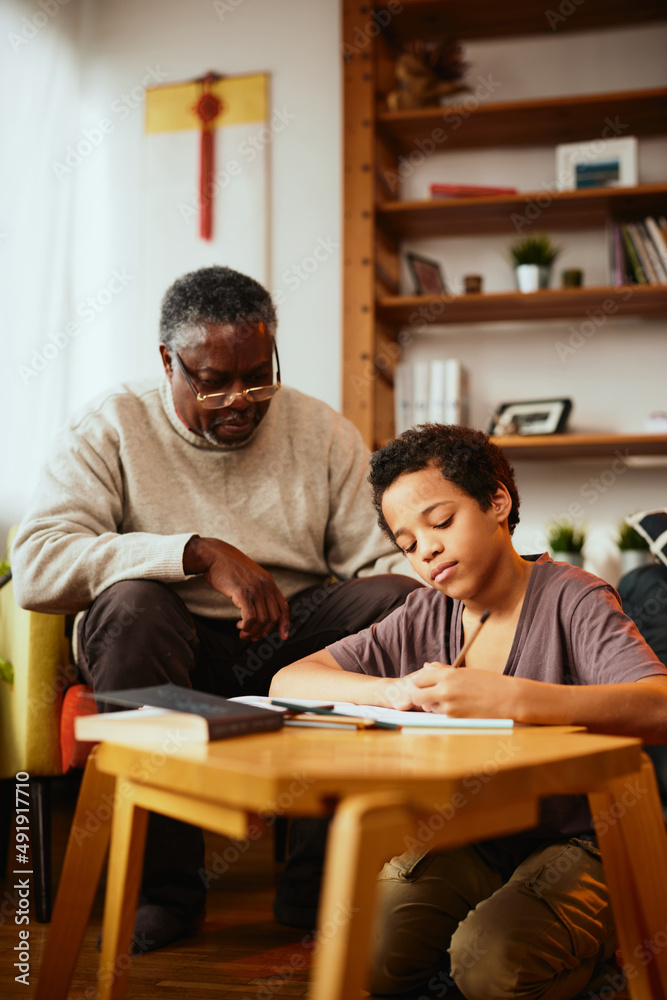 A grandfather looking at his grandchild's homework and checking on him at home.