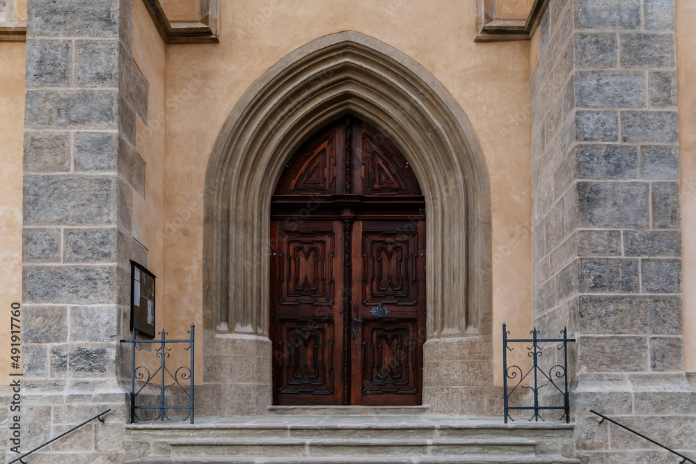 Kutna Hora, Central Bohemian, Czech Republic, 5 March 2022: Gothic stone Church of St. James or Kostel sv. Jakuba with wooden carved arched doors, medieval architecture at old town
