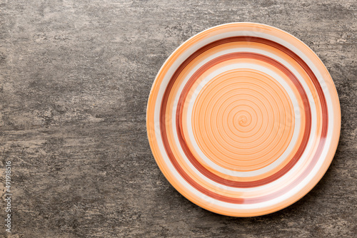 Top view of empty orange plate on cement background. Empty space for your design