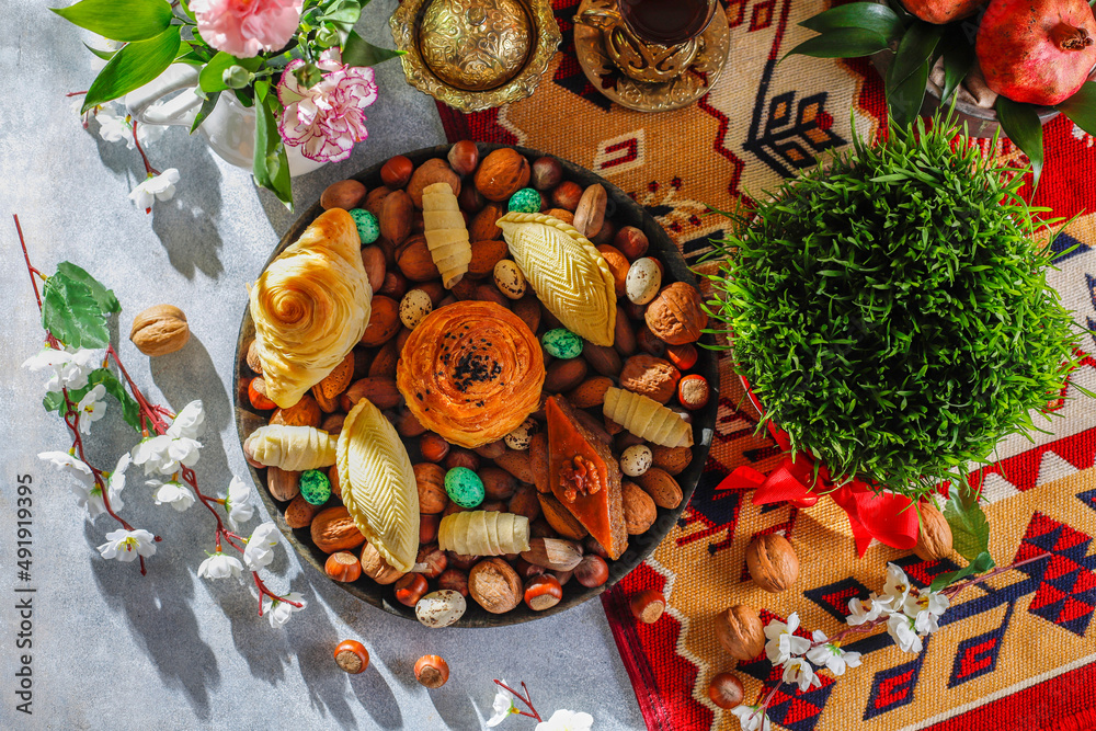 Traditional Azerbaijan spring holiday Nowruz tray with semeni - wheat grass, pakhlava, shekerbura,badambura,mutaki,gogal,flowers,dry fruits,spring flowers.