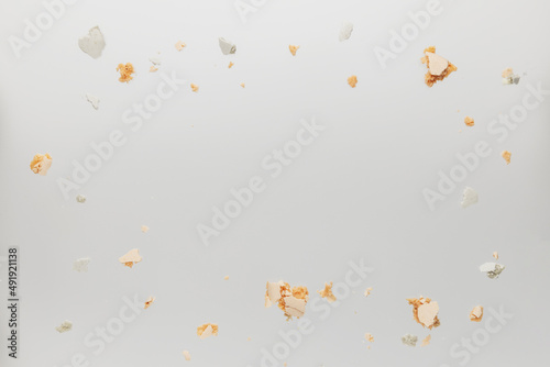 Pattern with white, yellow, gold macaron cookies lids, covers, parts and bites laying chaotically on the white table. Light beige or gray background. Broken cut, pieces with empty copy space area