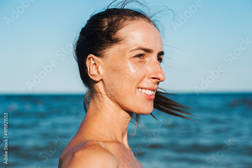 Smiling young woman at the sea looks to the side