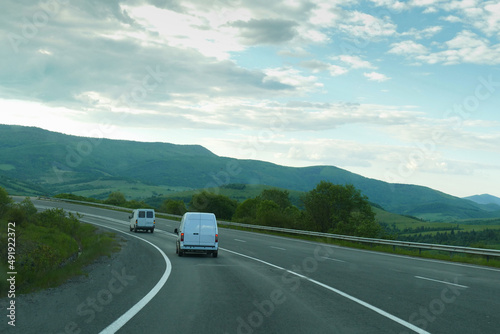 Cars drive along a scenic road. Beautiful track, good road. sign. Road through the forest. Auto travel.