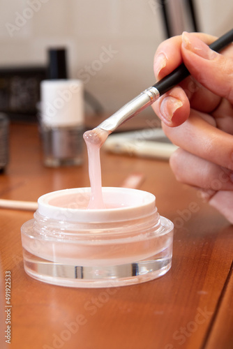 The hand holds the brush and touches the gel in the jar. Close-up. Image for beauty websites. Selective focus.