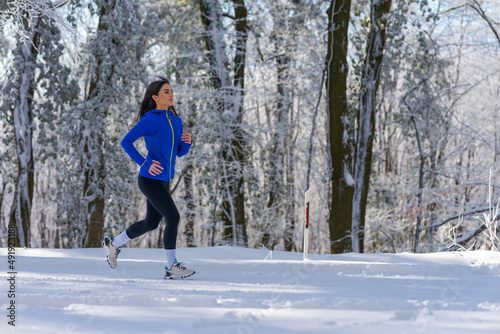 Sportswoman running in nature at snowy winter day. Winter fitness concept. © DusanJelicic