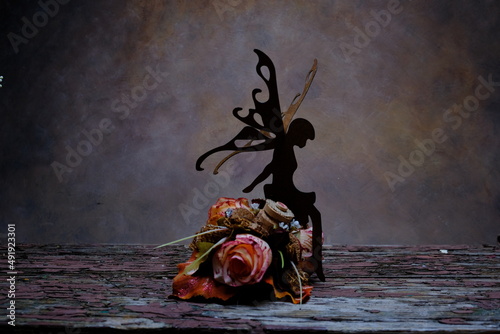 a little fairy perched on top of a bouquet of colorful roses