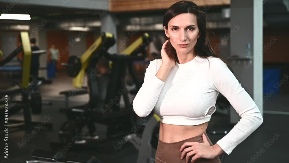 Portrait of young caucasian woman wearing sportswear bra and pants in fitness gym, sports and healthcare concept Portrait of young caucasian woman wearing sportswear bra and pants in fitness gym, sports and healthcare concept