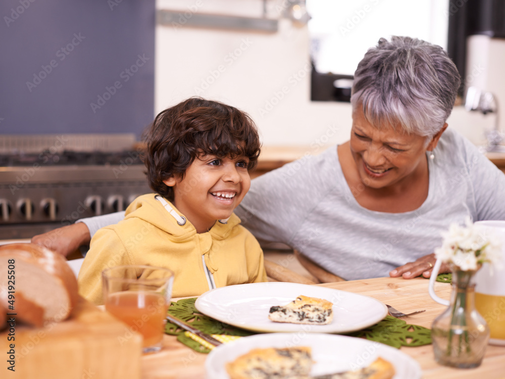 Grannys quiche is the best. A cute little boy eating a meal with his grandmother at home.