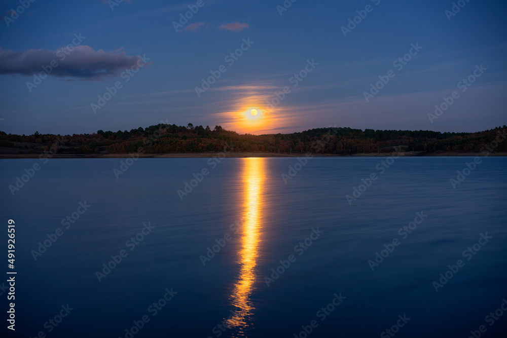 Full moon reflection on a lake at night in Sabugal Dam, Portugal
