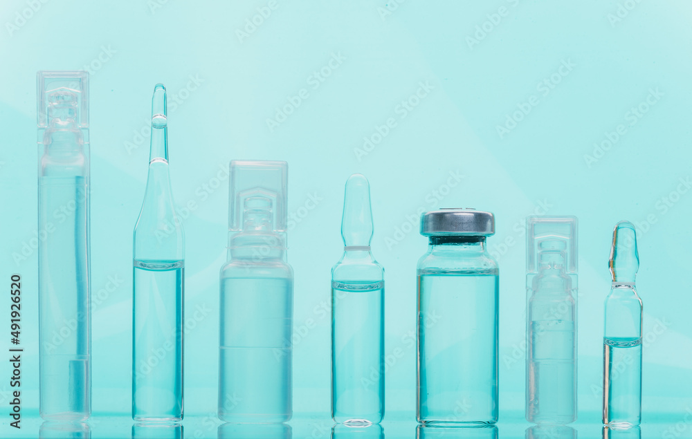 Glass medical ampoule vial for injection. Medicine is liquid sodium chloride with of aqueous solution in ampulla. Close up. Bottles ampule multicolor on background color and water. Human plasma. Glass medical ampoule vial for injection. Medicine is liquid sodium chloride with of aqueous solution in ampulla. Close up. Bottles ampule multicolor on background color and water. Human plasma.