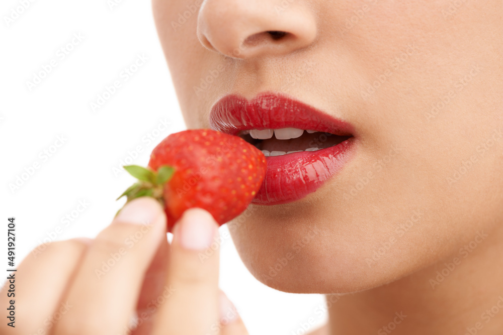 Bright red allure. Cropped closeup shot of a young woman with red lips eating a strawberry. Bright red allure. Cropped closeup shot of a young woman with red lips eating a strawberry.